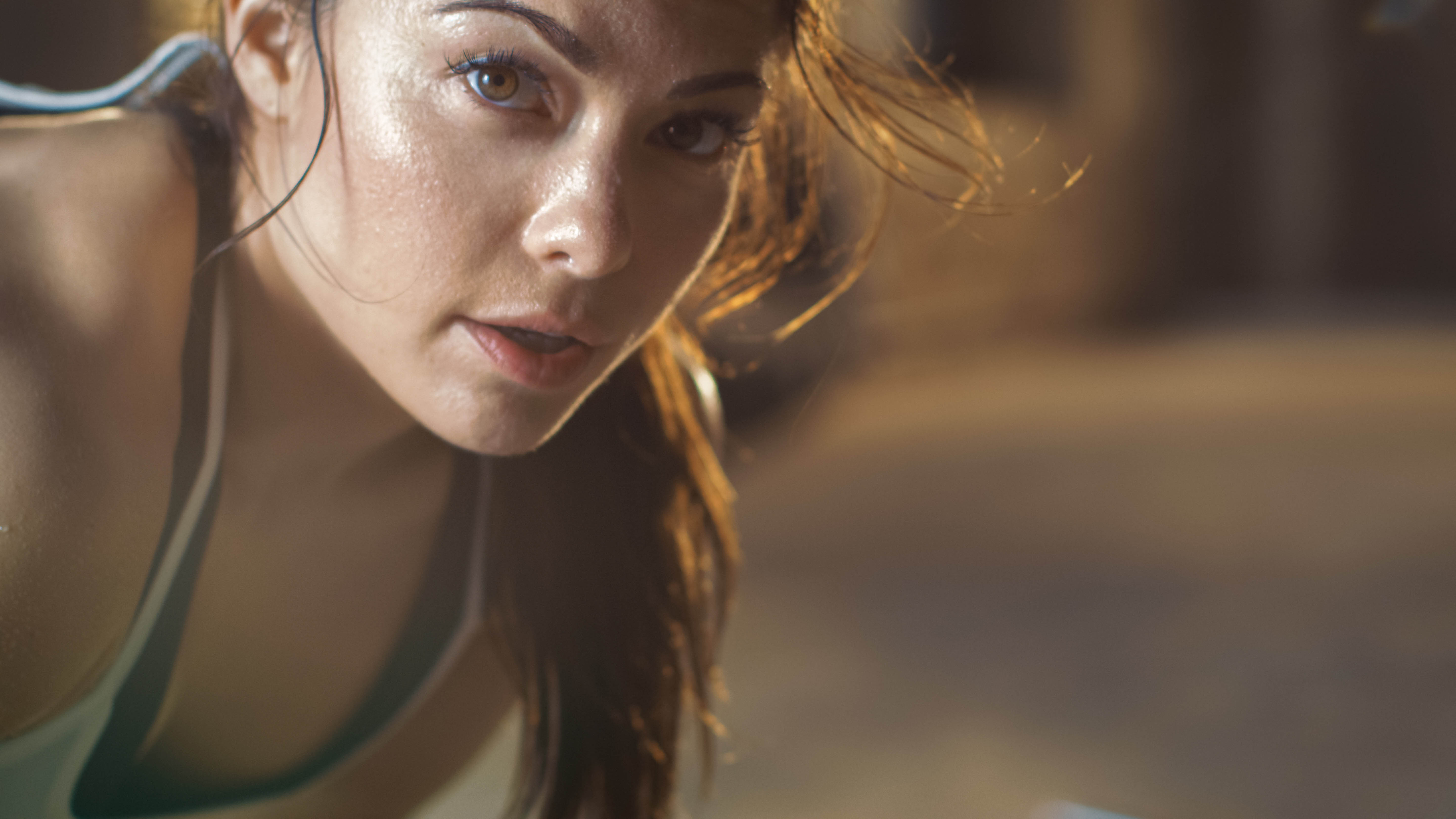 Sweaty, active woman hunched over stares into the camera, close-up